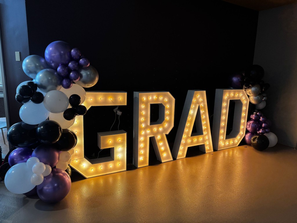 Balloon decor and marquee letters that spell out "Grad"