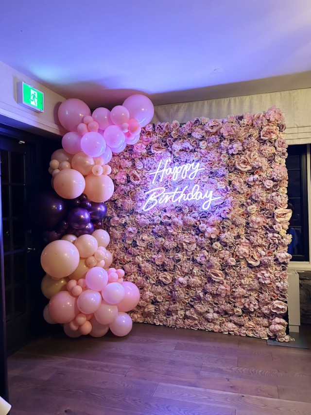 balloon garland, flower wall, and neon sign